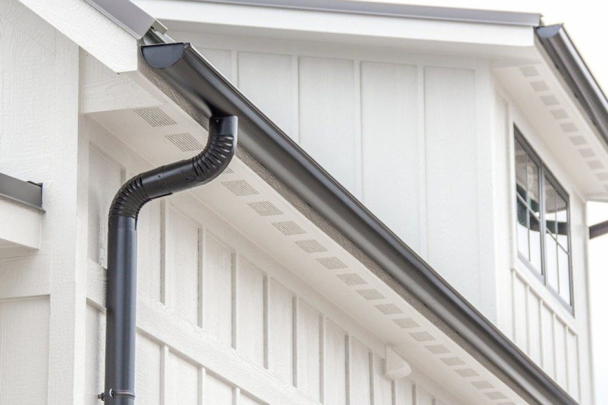 A clean black seamless gutter system installed on a white Southern Maryland home
